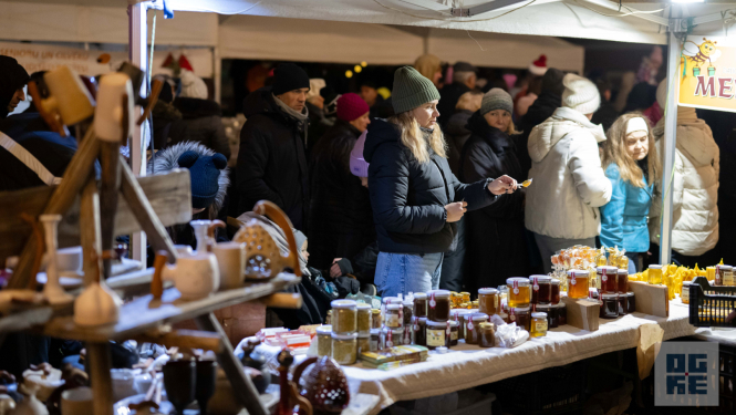 Gadatirgus apmeklētāji aplūķo priekšplānā izvietotos stendus ar māla izstrādājumiem un biškopības produktiem