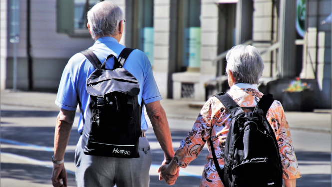 Seniori ar mugursomām sadevušies rokās