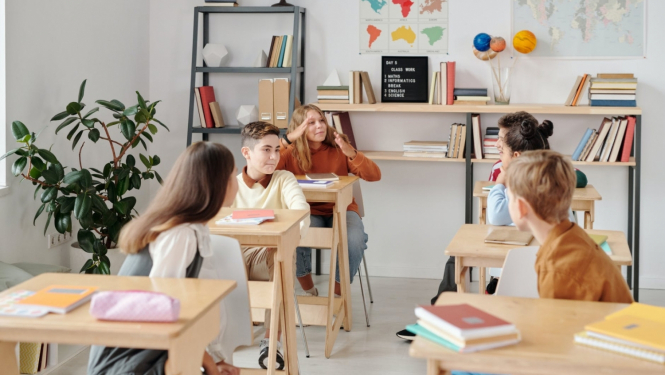 Pieci skolēni sēž klasē pie soliem