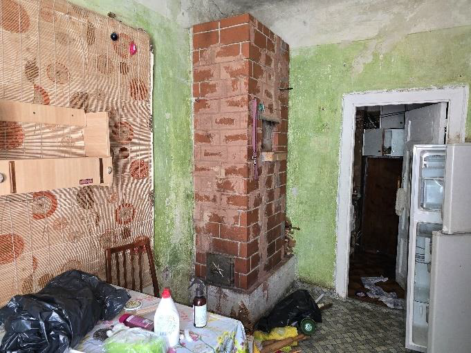 Dzīvokļa telpa ar mūrētu krāsni, mēbelēm un ledusskapi