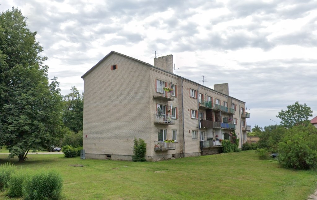 Trīsstāvu daudzdzīvokļu ēka, apkārt zāliens