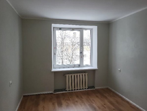 Istaba gaišos toņos ar logu un radiatoru