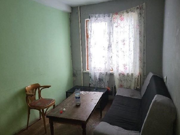 Istaba ar logu, gaiši zaļu sienu, galdu, dīvānu un koka krēslu