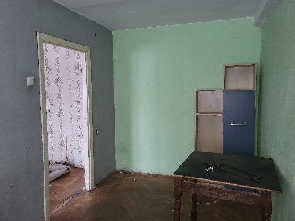 Istaba ar divām gaiši zaļā, sienām un dažām koka mēbelēm 