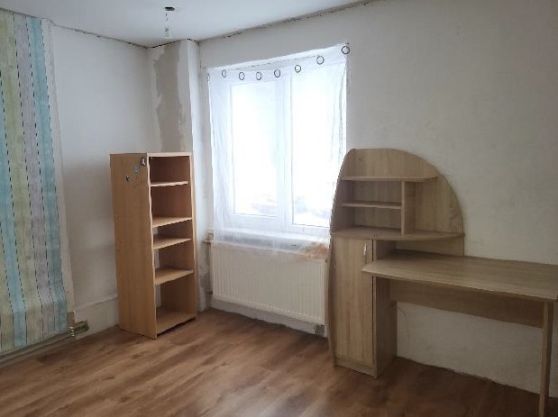 Istaba ar gaišas krāsas sienām, logu un dažām koka mēbelēm
