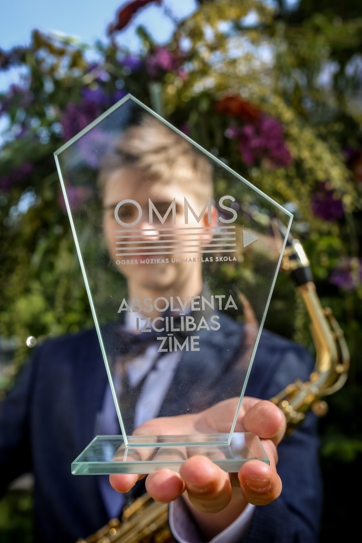 Absolvents tur rokā Ogres Mūzikas un mākslas skolas Absolventa izcilības zīmi