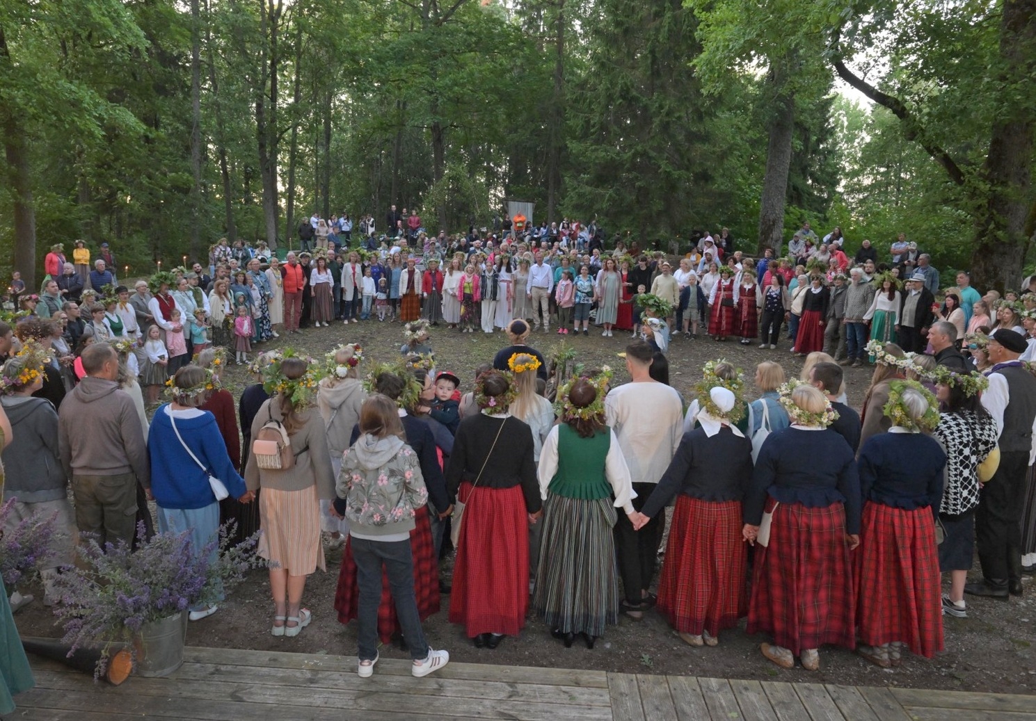 Cilvēki stāv aplī Plāteres pilskalnā 20.06.2024.