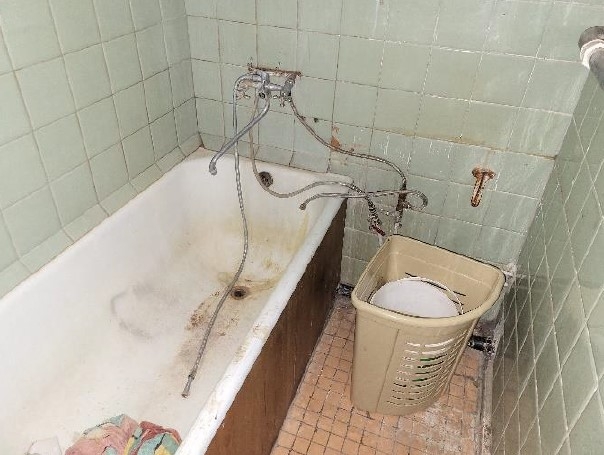 Vannas istaba ar gaiši zaļām sienas flīzēm un vannu