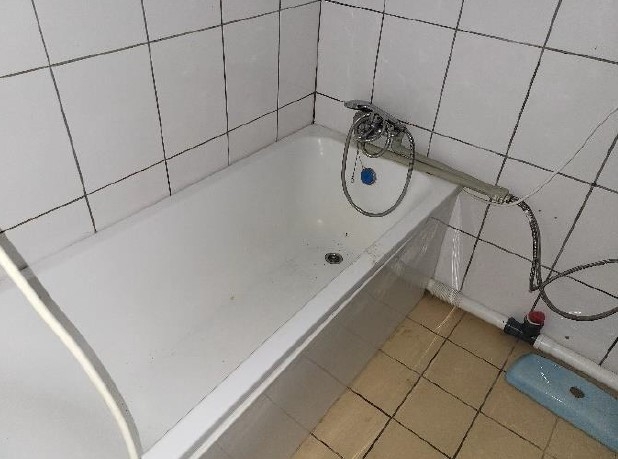 Vannas istaba ar baltas krāsas flīzēm un vannu