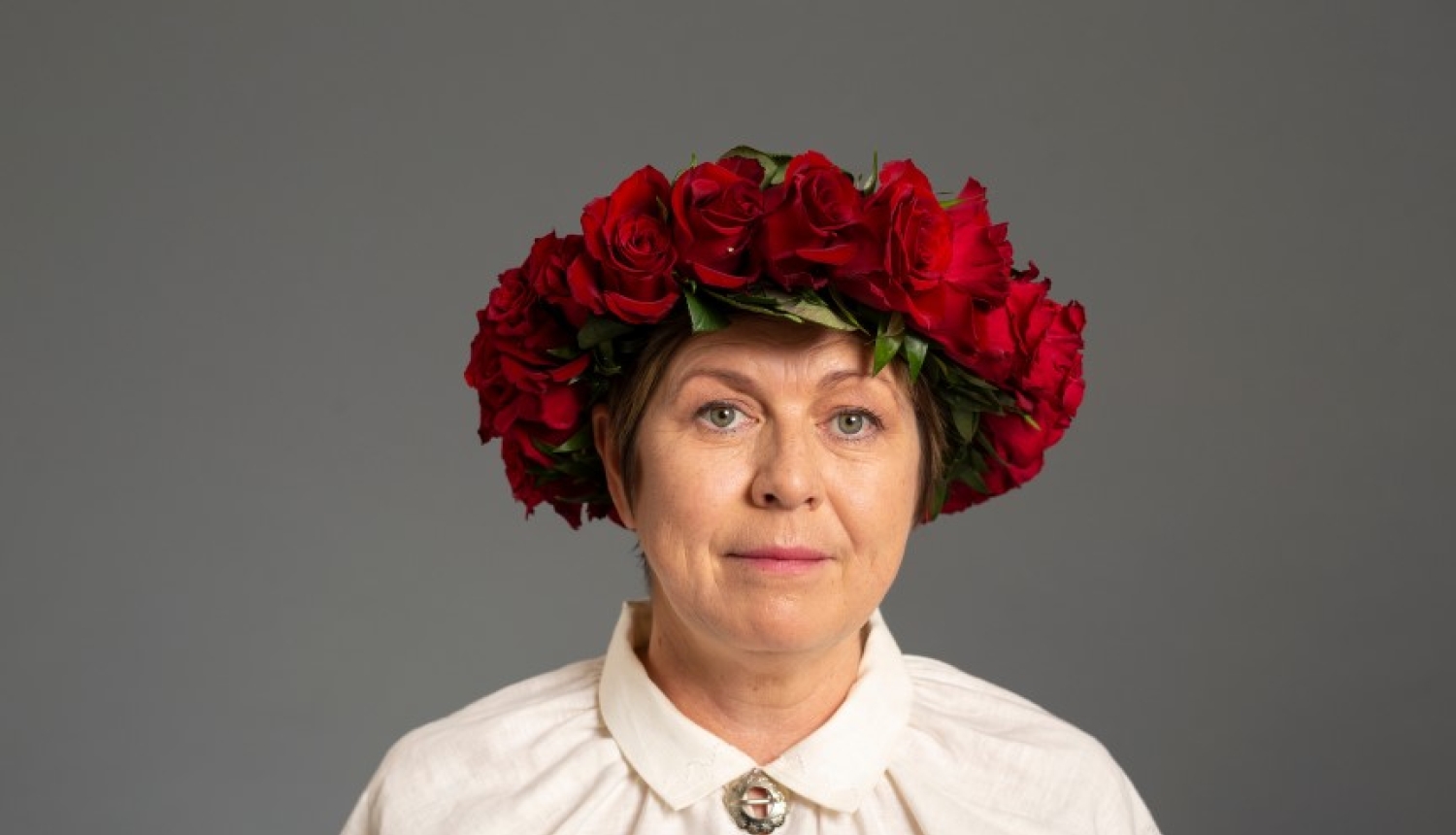 Noras Ikstenas foto ar sarkanu rožu vainagu
