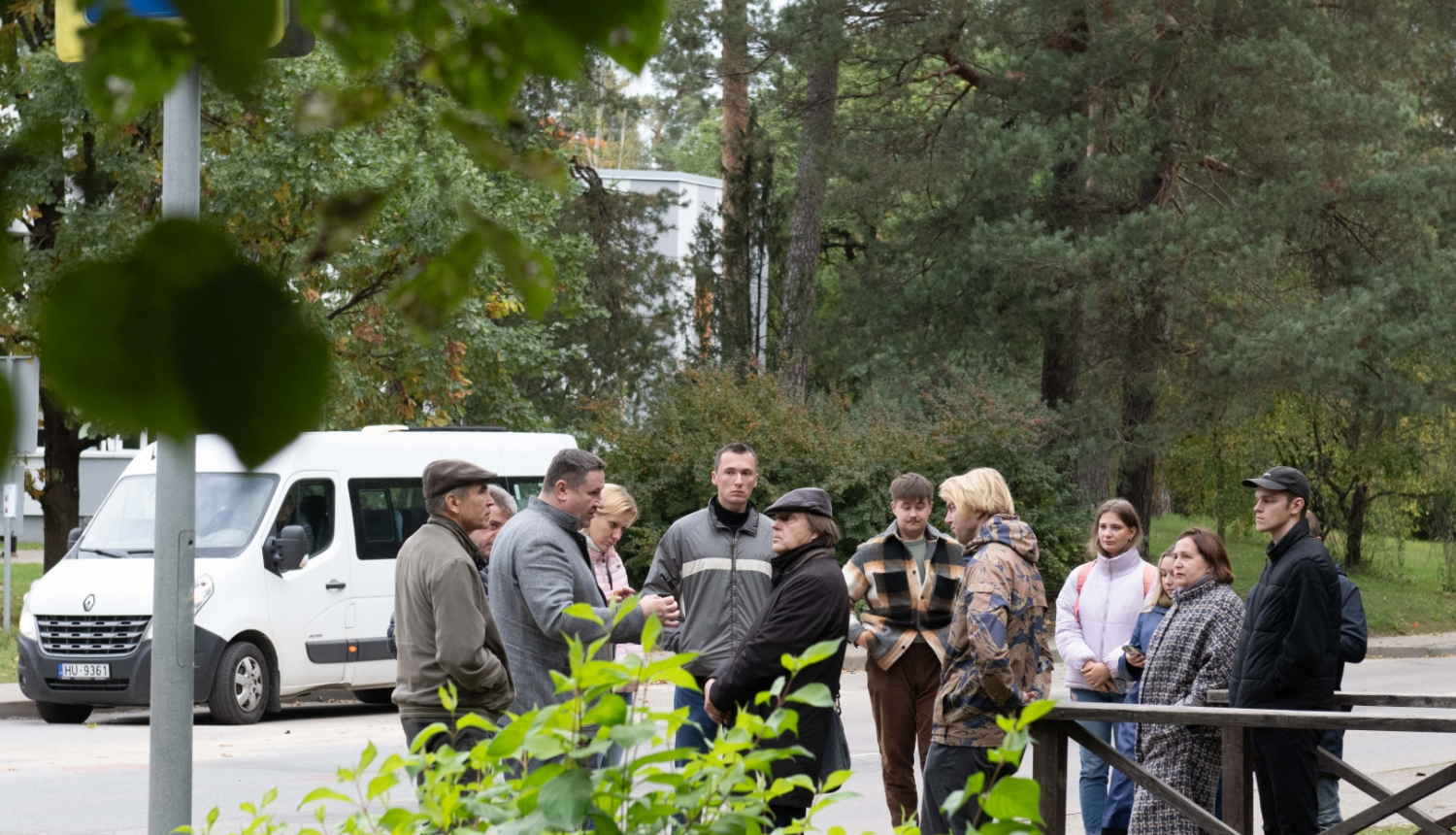 RTU profesori, studenti, Egils Helmanis stāv un sarunājas ielas malā, fonā balts mikroautobuss 09.10.2024.