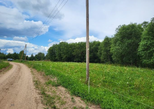 Zemes gabals - pļava ar ceļu un elektrības stabiem
