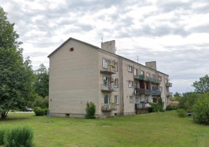Trīsstāvu daudzdzīvokļu ēka, apkārt zāliens