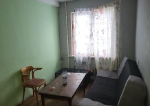 Istaba ar logu, gaiši zaļu sienu, galdu, dīvānu un koka krēslu