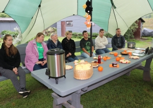 Sociāla uzņēmēja pie Zelta liepas darbinieki sēž uz soliņa pie Lapsas mājas siera ražotājiem 19.06.2024.