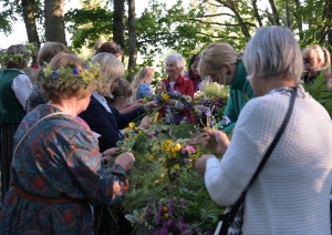 Cilvēki pin Jāņu vainagus Plāteres pilskalnā 20.06.2024.
