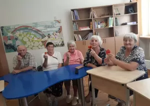 5 seniori sēž pie galda ar filca sirsniņām rokās 08.2024.