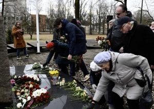 Cilvēki noliek ziedus pie politiski represēto piemiņas akmens Ogrē