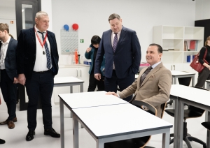 Ministrs sēž skolas solā, blakus stāv Egils Helmanis un Dainis Širovs
