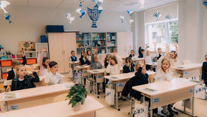 1. septembris Ogres novada skolās. Attēlā 1. klases skolnieki sēž solos ar paceltām rokām