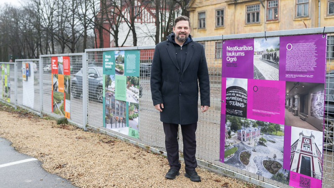 Ogres novada pašvaldības domes priekšsēdētāja vietnieks A. Krauja lielformāta izstādes atklāšanā pie Neatkarības laukuma plakāta