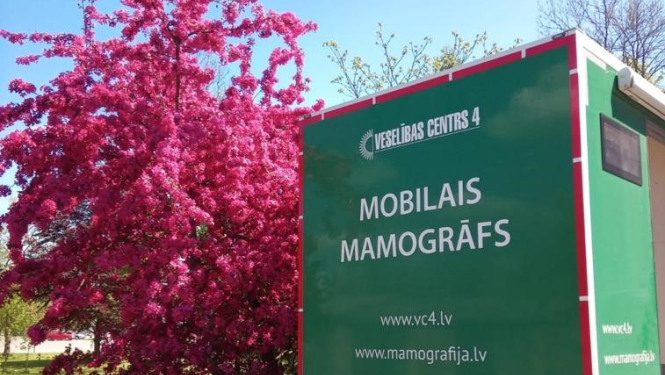 Mobilā mamogrāfa automobilis pie ziedoša koka