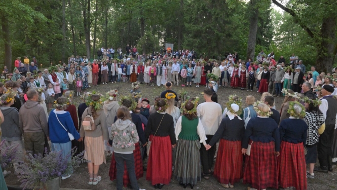 Cilvēki stāv aplī Plāteres pilskalnā 20.06.2024.