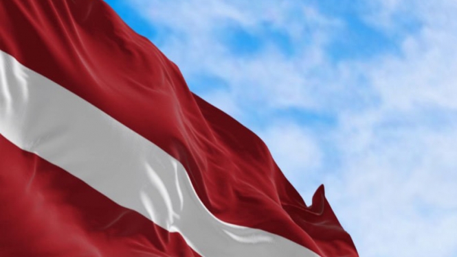 Latvijas Valsts karogs uz zilu debesu fona