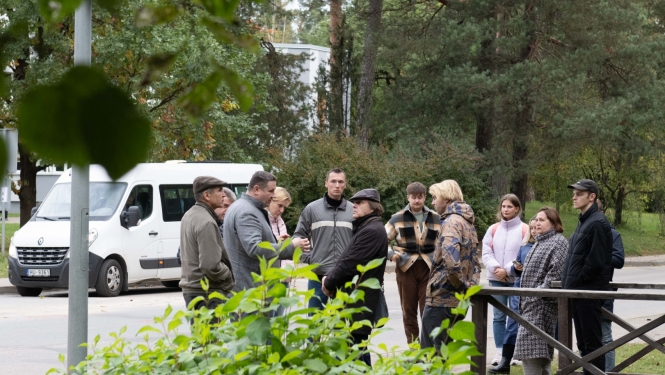 RTU profesori, studenti, Egils Helmanis stāv un sarunājas ielas malā, fonā balts mikroautobuss 09.10.2024.