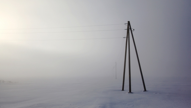 Elektrības stabi ar vadiem sniegotā laukā