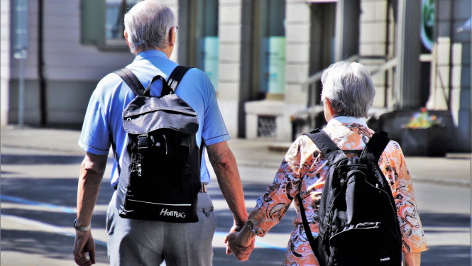Seniori ar mugursomām sadevušies rokās