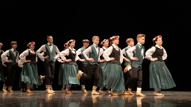 Skolēnu tautas deju skates dalībnieki uz skatuves tautas tērpos