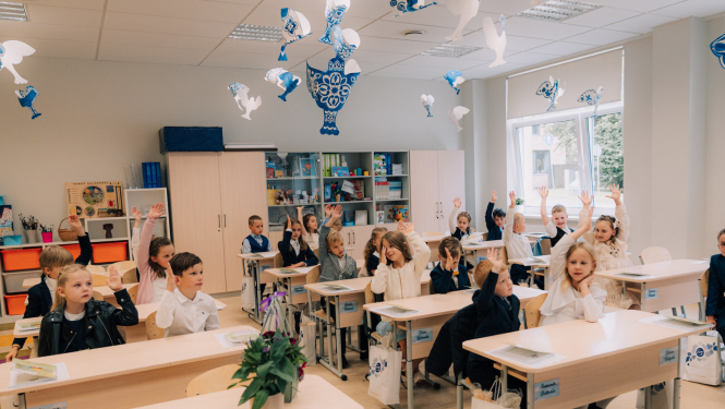 1. septembris Ogres novada skolās. Attēlā 1. klases skolnieki sēž solos ar paceltām rokām