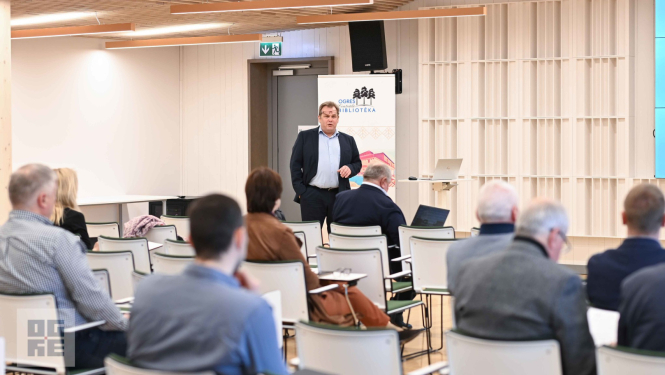 Semināra dalībnieki Ogres Centrālās bibliotēkas zālē klausās SIA “Latvijas standarts” valdes locekļa Ingara Pilmaņa stāstījumu