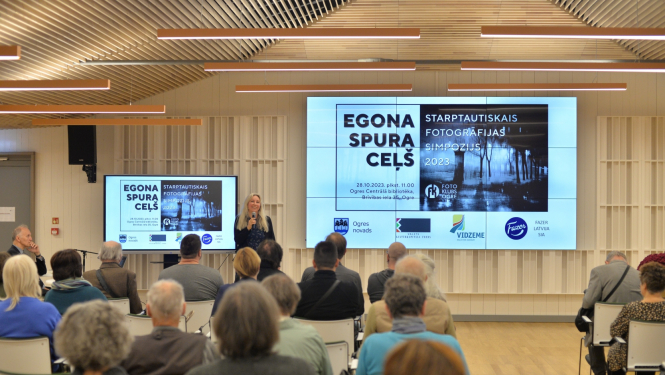 Cilvēki sēž, riekšā runā lektors Simpozijā Egona Spuras ceļš 2023. gads