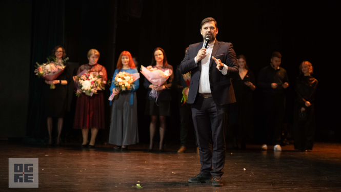 Ogres novada pašvaldības domes priekšsēdētājs Andris Krauja saka uzrunu 2026. gada Ogres Valsts ģimnāzijas žetonvakarā. Aiz viņa - ģimnāzijas skolotāji