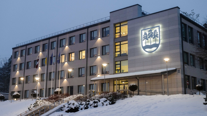 Ogres novada pašvaldības domes ēka ziemā, izgaismota krēslas stundā.