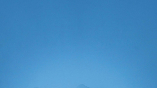 Attēls rakstam par iespējām apgūt dronu pilotēšanu. Attēlā lidojošs drons uz zilas debess fona