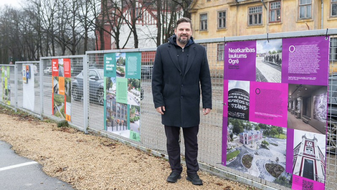 Ogres novada pašvaldības domes priekšsēdētāja vietnieks A. Krauja lielformāta izstādes atklāšanā pie Neatkarības laukuma plakāta