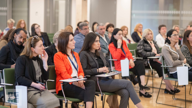 Mācību vizītes dalībnieki klausās prezentāciju Ogres Centrālās bibliotēkas zālē