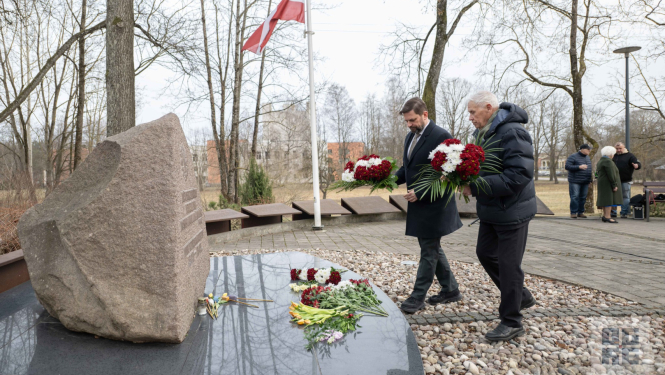 Ogres novada pašvaldības domes priekšsēdētājs Andris Krauja un Ogres Politiski represēto kluba vadītājs Ivars Kaļķis 2026. gada 25. martā noliek ziedus pie piemiņas akmens Ogrē