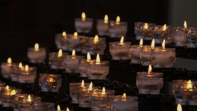 Aizdedzinātas svecītes, saliktas rindiņā.