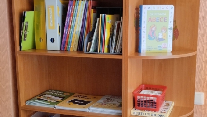 Grāmatu plaukts ar informatīvajiem materiāliem vecākiem, kuri neizvēlas bērnu izglītot pirmsskolas izglītības iestādē