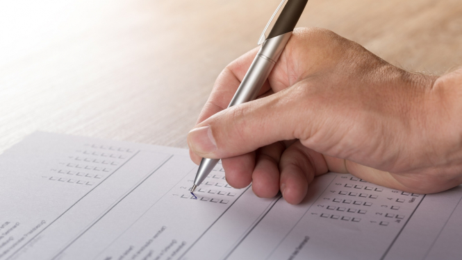 Turot rokā pildspalvu, tiek aizpildīta aptaujas anketa 