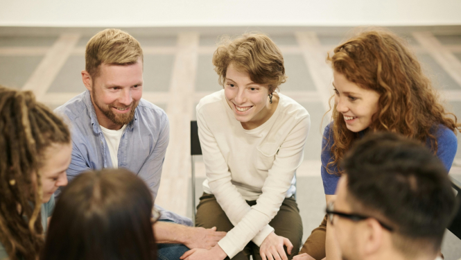 Jauni vīrieši un sievietes sēž aplī un diskutē