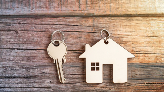 Atslēga un breloks mājas izskatā uz koka fona