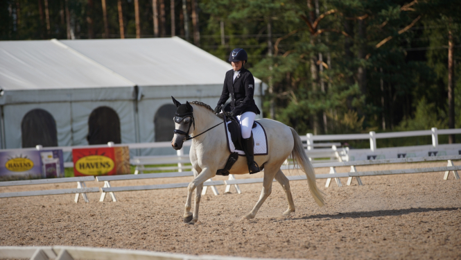 Meitene tumšā tērpā jāj uz zirga 08.2024.