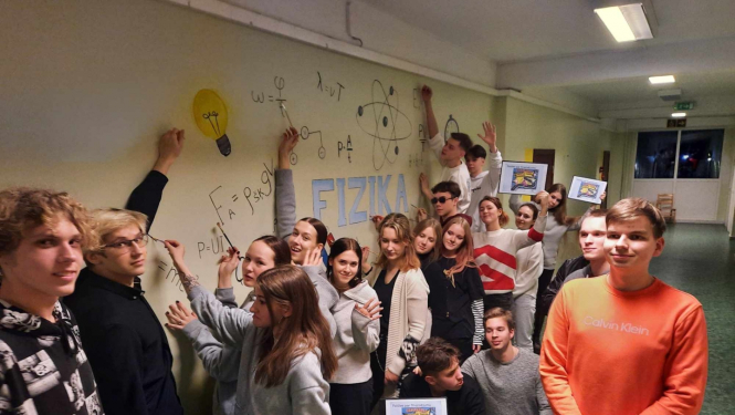 Aptuveni 20 jaunieši pie izveidotās fizikas likumu sienas