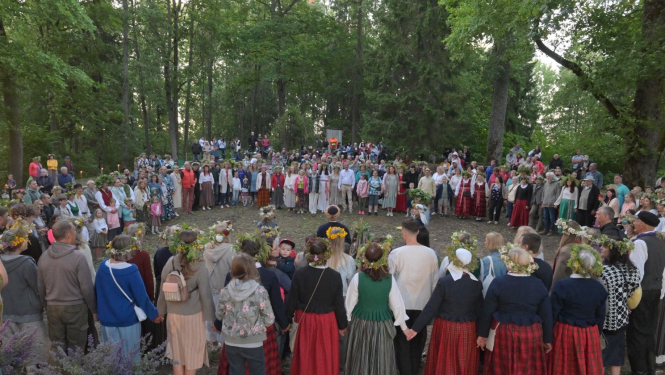 Cilvēki stāv aplī Plāteres pilskalnā 20.06.2024.