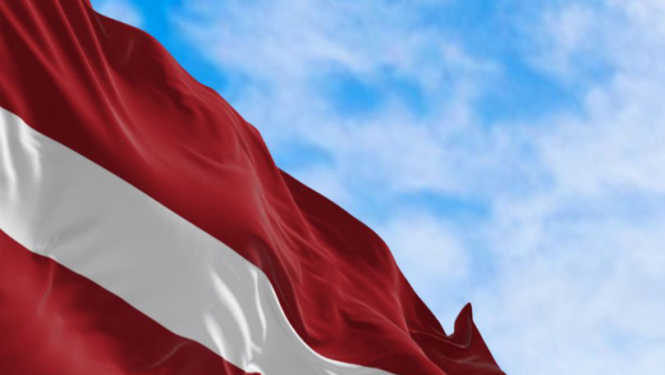 Latvijas Valsts karogs uz zilu debesu fona